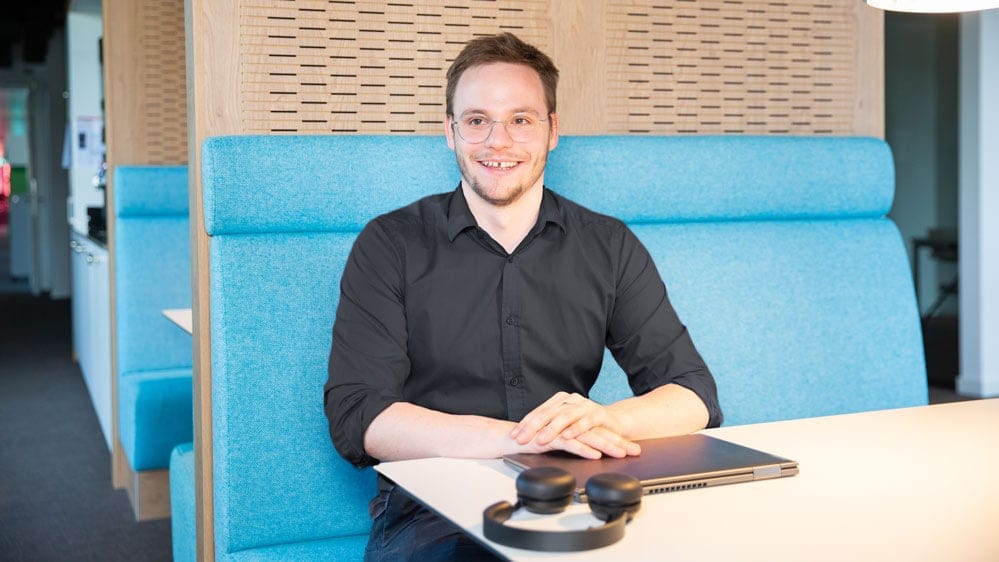 Un homme pose en souriant avec son ordinateur portable