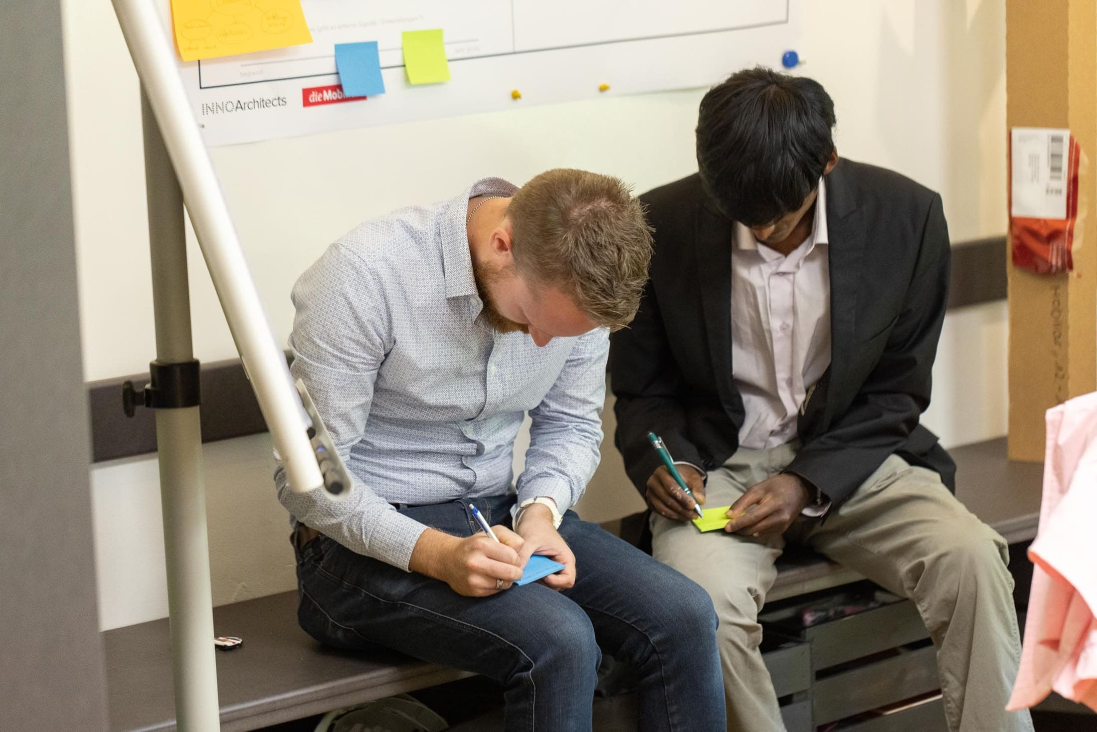 Due uomini scrivono su Post It’s nel Forum Mobiliare