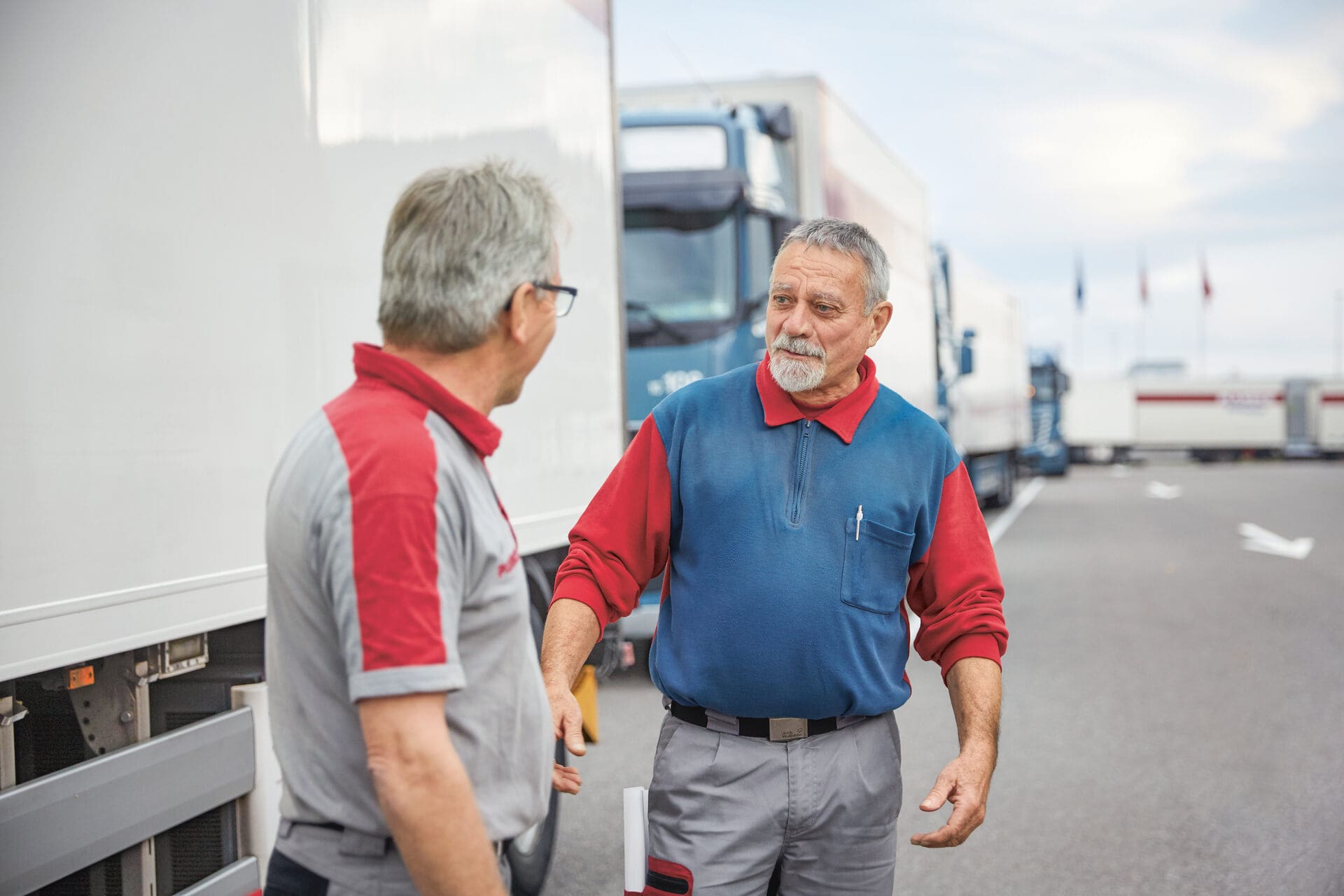 Due uomini discutono davanti a una fila di camion.