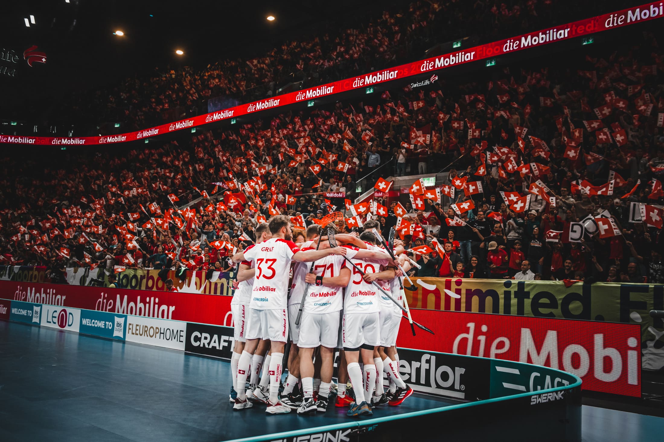 La squadra nazionale svizzera maschile di unihockey segna un gol e festeggia davanti al pubblico locale