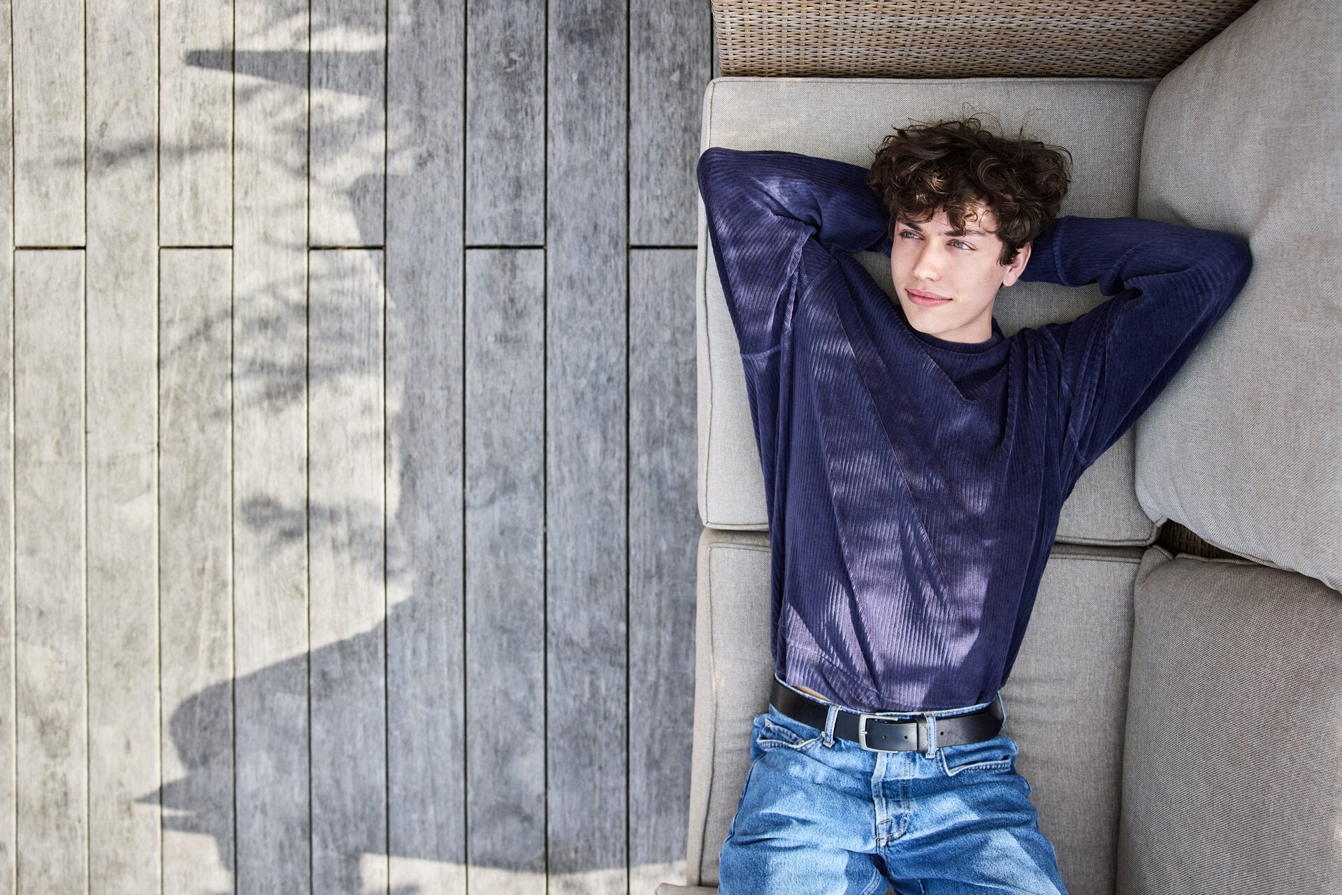 Image symbolisant l’adoption des enfants du ou de la partenaire: un jeune est allongé sur un canapé d’extérieur et regarde vers le ciel d’un air satisfait.