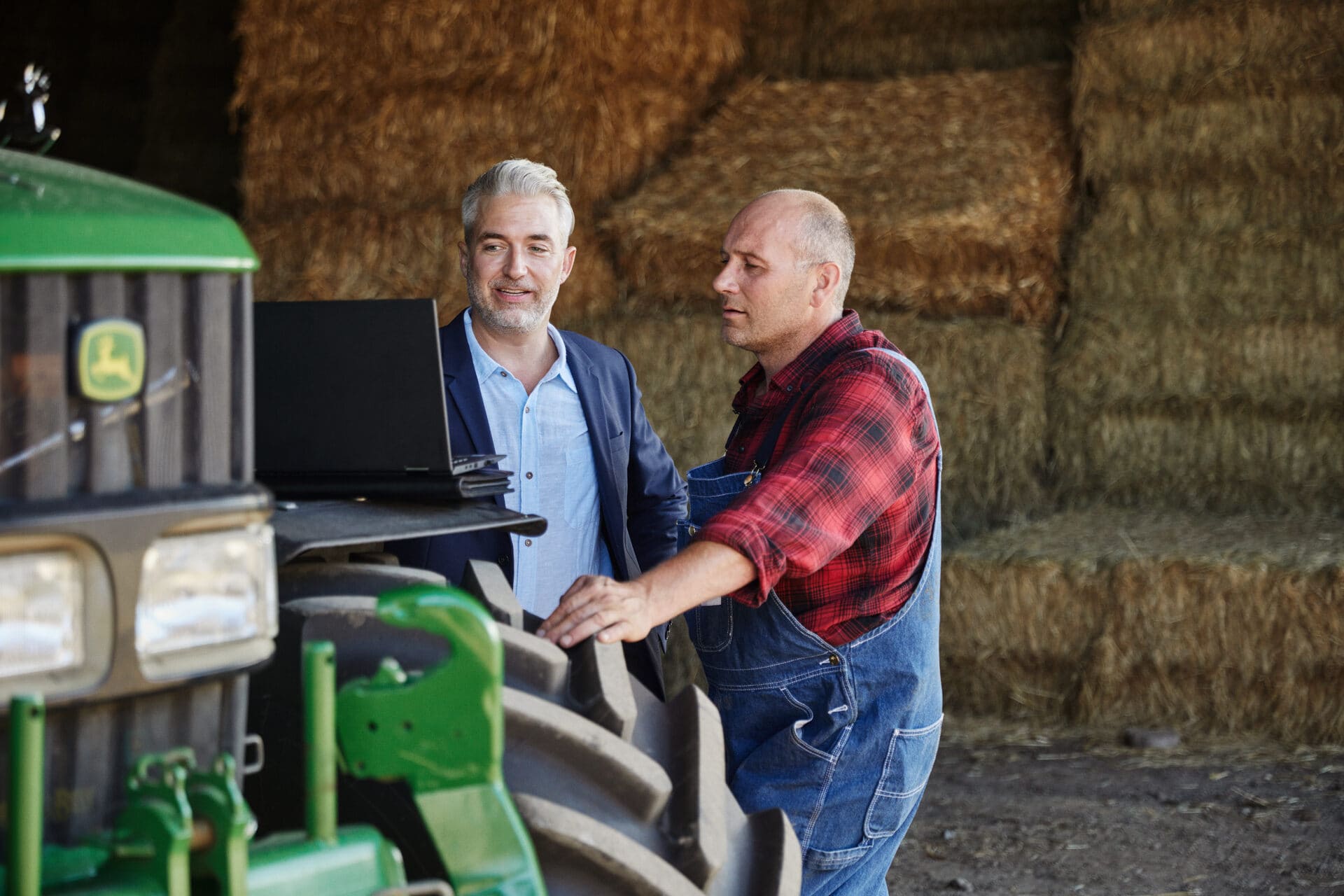 Berater unterhält sich mit einem Landwirt menem einem Traktor