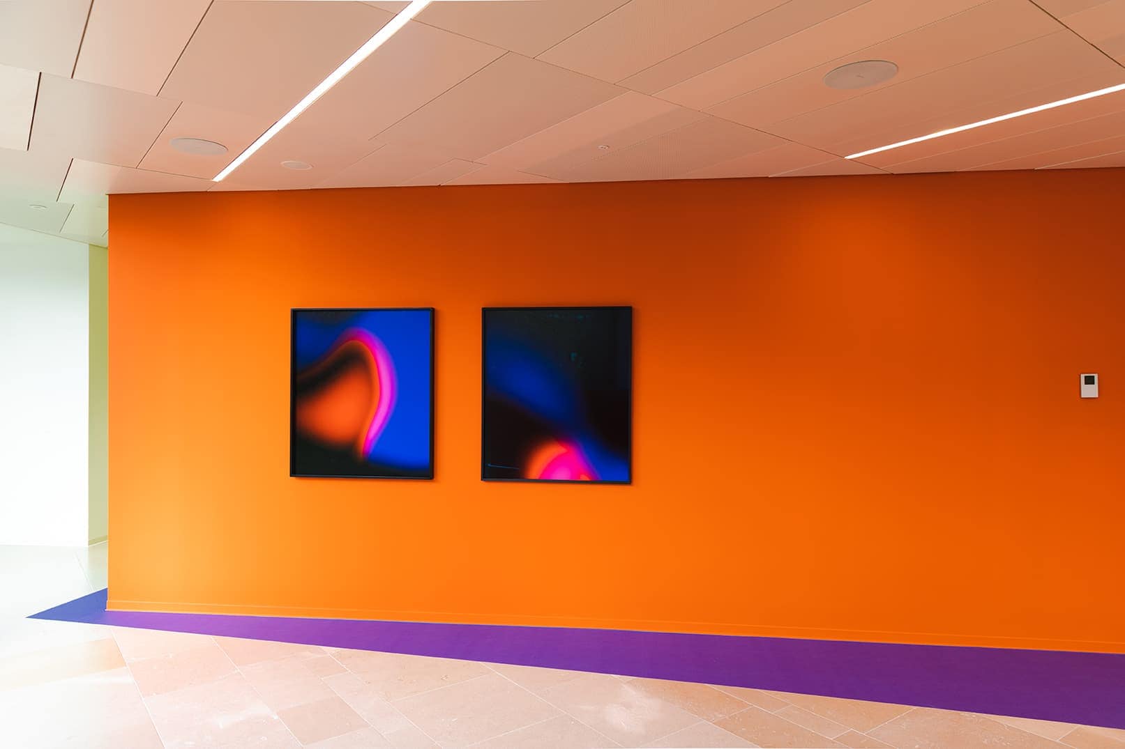 Deux tableaux bleus devant un mur orange dans le cadre de l’exposition «L’art et le développement durable à la Mobilière»