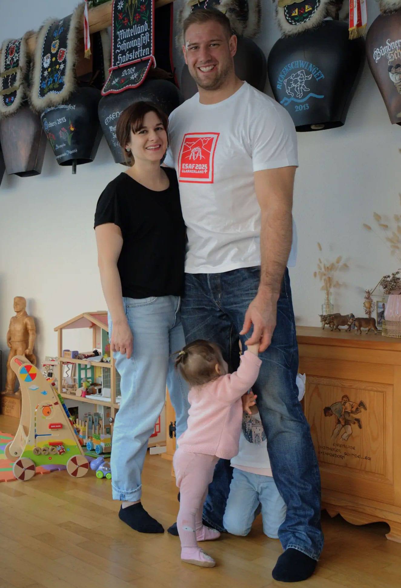 Roger Rychen, sa compagne et leurs deux jeunes enfants se retrouvent dans un salon joliment décoré avec des trophées de lutte.