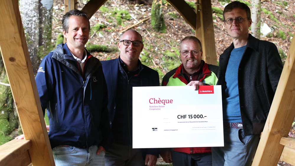 4 personnes posent avec un chèque dans les mains devant la caméra.