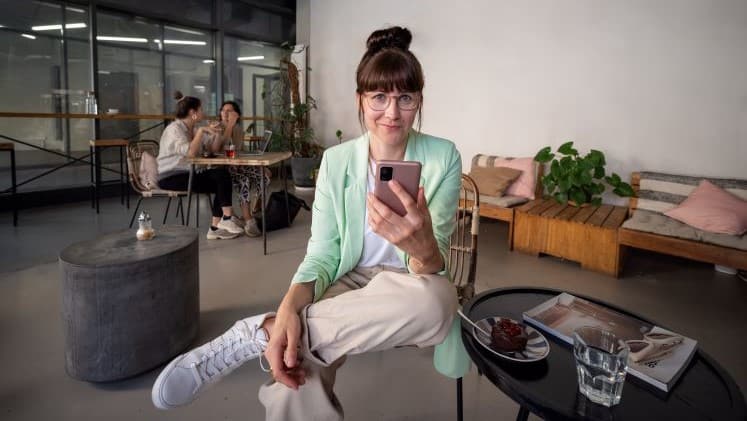 Frau auf Stuhl mit Smartphone in der Hand
